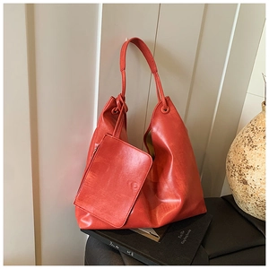 Detail view of orange-red soft PU leather tote bag with a matching small zipper pouch
