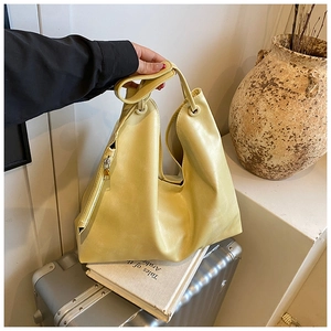 Detail of soft cream yellow PU leather tote bag with wide strap and side zipper design