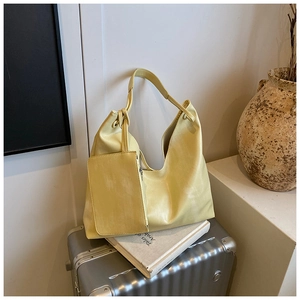 Detail of soft yellow PU leather tote bag with matching inner pouch on a silver suitcase