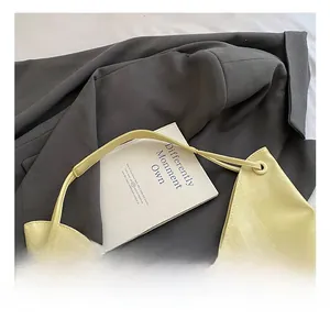 Detail of light yellow tote bag with metal ring hardware on gray blazer