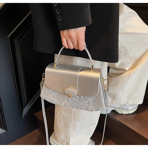 Detail of silver metallic textured crossbody bag with snake pattern and M logo buckle