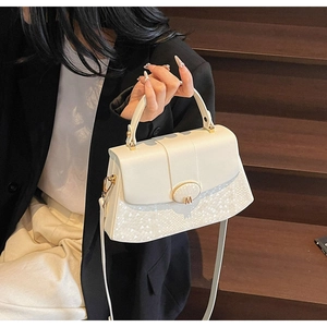 Detail of creamy white crossbody bag with snake-embossed texture and golden M logo