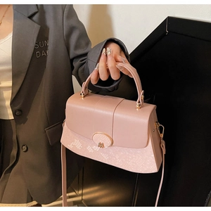 Detail of light pink leather handbag with geometric texture and golden M buckle