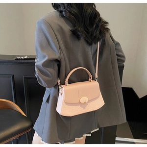 Detailed view of a pink textured handbag with a gold buckle worn by a model