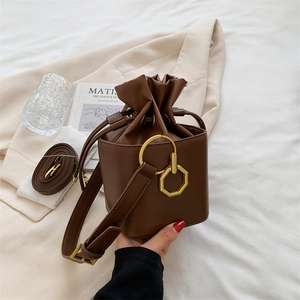 Sac seau marron foncé avec cordon de serrage et pendentif doré sur fond esthétique