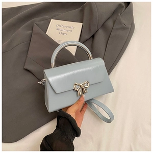 Close-up of a light blue mini bag with silver bow buckle and metal handle on a blazer