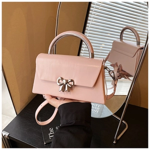 Detailed mirror view of a pink leather bag with silver metal handle and bow clasp