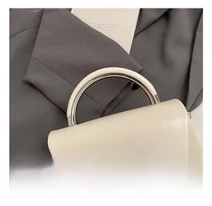 Detail showing cream leather handbag with silver bow buckle and semi-circle metal handle