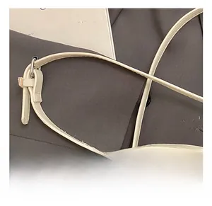 Detail showing an adjustable cream faux leather shoulder strap with silver metal buckle