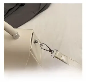 Detailed close-up of silver metal hardware and stitching on a cream shoulder bag