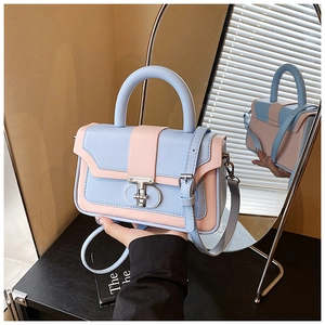 Detail view of the silver circular metal buckle on the two-tone blue and pink handbag