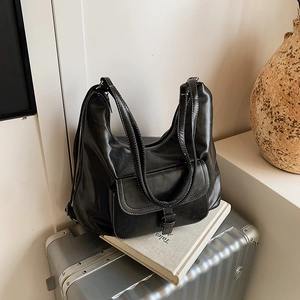 Retro black leather backpack with white stitching placed on a silver suitcase