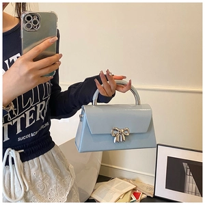 Detail of light blue patent leather bag with silver bow buckle in a mirror selfie view
