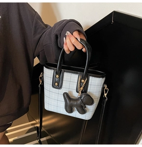 Detail of light blue checkered bucket bag with black trim and cute puppy charm