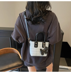 Rear view of model wearing a small blue and white plaid tote bag with black trim