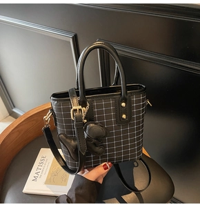 Close-up of black plaid handbag featuring a white grid pattern and golden hardware details