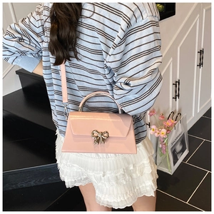 Detail of light pink patent leather mini bag with silver bow buckle and metal handle
