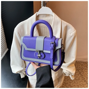 Detail of purple and grey contrast handbag featuring a silver irregular metal turn-lock buckle