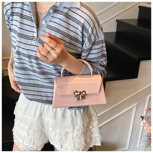 Detailed view of pink leather handbag featuring a stylish silver bow metal clasp