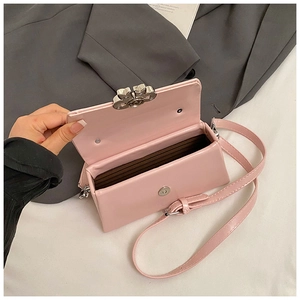 Detail view of pink leather crossbody bag with metal flower clasp and interior storage