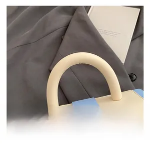 Detail of blue and beige handbag featuring a thick rounded handle and fine PU leather texture