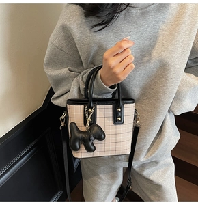 Close-up of checkered mini tote bag with leather trim and a cute puppy charm