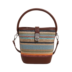 Bohemian striped woven bucket bag with brown leather handles and a metallic twist lock