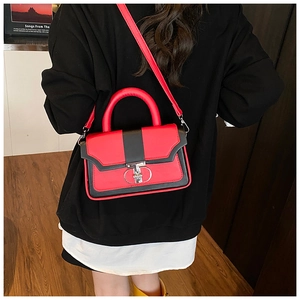 Detailed view of red and black crossbody bag with vintage metal lock on wood floor