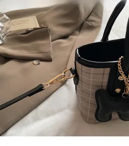 Detail of the golden D-ring hardware and black grid fabric on a luxury crossbody bag