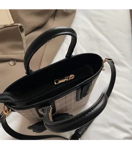 Detail view of smooth metal zipper and plaid fabric texture on a crossbody bag