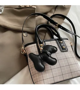 Detail of checkered tote bag with leather trim and a cute black puppy bag charm