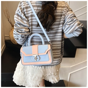 Detail of pink and blue color-block crossbody bag with metal CD logo buckle on model