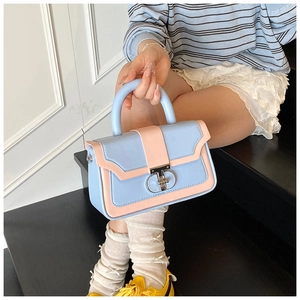 Detail of a light blue and pink crossbody bag with silver double-ring lock decoration