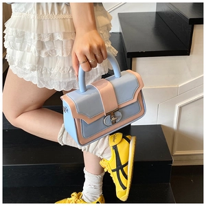 Fashionable blue and pink crossbody handbag with silver buckle held by a model