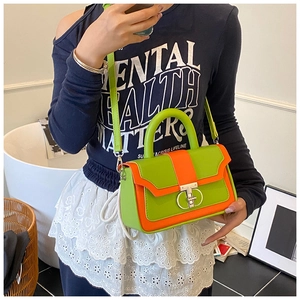 Detail of green and orange contrast handbag with round metal buckle and detachable strap