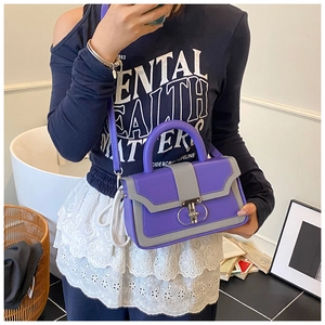 Detail of a structured color-block handbag in purple and grey with metal buckle