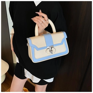 Detail of elegant two-tone cream and blue handbag with a metallic oval twist lock
