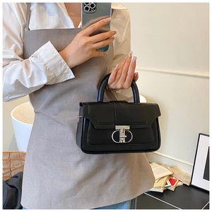 Detail of a black leather handbag with silver metallic clasp held by a model in a mirror