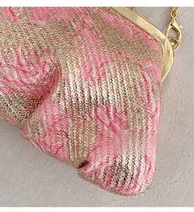 Detail of pink and gold brocade texture on clutch bag with golden chain and clasp