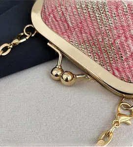 Detailed view of pink jacquard lipstick bag featuring golden kiss-lock and metal chain