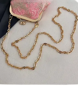 Close-up of golden metal chain strap and pink woven texture fabric on trendy handbag