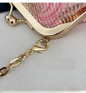 Close-up of pink and gold woven bag detail with detachable metal chain hook and clasp