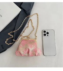 Detailed close-up of woven texture mini kiss-lock bag with gold chain and metal clasp