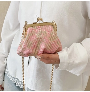 Close-up of a pink tweed clasp bag with gold metal frame and delicate chain strap