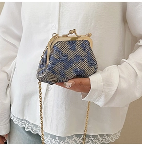 Detail of vintage blue jacquard weave bag with gold kiss-lock closure and metal chain