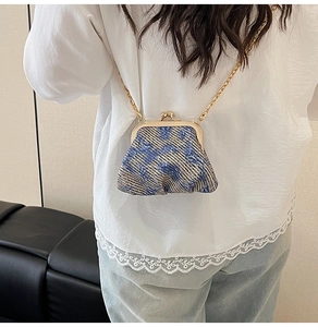 Detail of retro textured woven lipstick bag with gold clasp and chain on white lace top