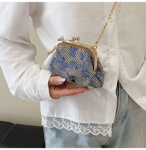 On-body view of a mini blue and gold tweed chain bag with a classic metal kiss-lock