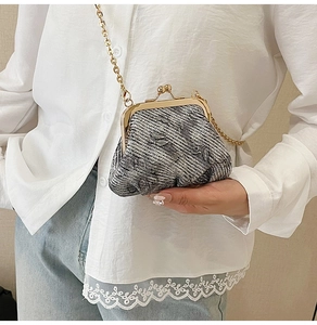 Detail of tweed crossbody mini bag with gold-tone kiss lock and elegant chain strap