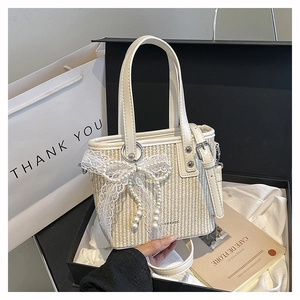 Detail of straw woven bucket bag with lace bow and pearls in an elegant gift box