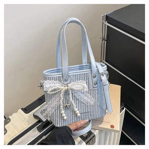 Detail of blue and white woven handbag with pearl lace bow and heart-shaped metal pendant